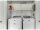 Bright laundry room with white washer and dryer and ample white shelving for storage at 19833 N 47Th Ln, Glendale, AZ 85308