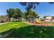 Bright, inviting playground in a well-maintained community with lush green grass and mature shade trees at 19833 N 47Th Ln, Glendale, AZ 85308