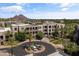 Serene aerial view of the condo complex with manicured circular drive, complemented by scenic mountain views in the background at 2 Biltmore Est # 313, Phoenix, AZ 85016