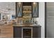 Modern bar area featuring wine fridge, mirrored backsplash, and stylish glassware and lighting at 2 Biltmore Est # 313, Phoenix, AZ 85016