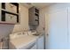 Functional laundry room equipped with modern washer, dryer, and overhead storage at 2033 E Hillery Dr, Phoenix, AZ 85022