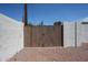 Wooden gate providing access to a gravel-covered area, set between white block walls at 228 E Del Rio Dr, Tempe, AZ 85282