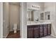 Bathroom with dual sinks, wood cabinets, and a separate toilet room at 22812 N 123Rd Dr, Sun City West, AZ 85375