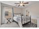 Bedroom with a black metal bedframe, ceiling fan, and window with curtains at 22812 N 123Rd Dr, Sun City West, AZ 85375