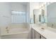 Bright bathroom featuring a built-in tub, a vanity with sink and large window at 2629 E Verbena Dr, Phoenix, AZ 85048