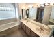 Bathroom with a soaking tub, double sink vanity, and a large mirror at 2629 E Verbena Dr, Phoenix, AZ 85048