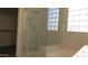 Bathroom featuring tiled shower with glass door, block window, and soaking tub at 29462 N 126Th Ln, Peoria, AZ 85383