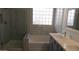 Modern bathroom featuring a tiled shower, block window, soaking tub, and double sink vanity at 29462 N 126Th Ln, Peoria, AZ 85383