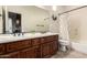 Bathroom featuring double sinks, a large mirror, floral accents, and a shower-tub combo with decorative curtain at 32525 N 41St Way, Cave Creek, AZ 85331