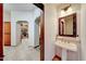 Stylish powder room featuring a pedestal sink, decorative mirror, and warm lighting adjacent to the kitchen and hall at 36601 N Mule Train Rd # 45B, Carefree, AZ 85377