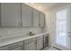 Butler's pantry boasting gray cabinets with brass hardware, a beverage fridge, and an exterior door at 38082 W Santa Barbara Ave, Maricopa, AZ 85138