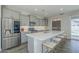 Modern kitchen boasts stainless steel appliances, a spacious island with stools, and backyard access to a pool at 38082 W Santa Barbara Ave, Maricopa, AZ 85138