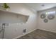 Bright laundry room featuring a shelf, plant, utility connections, decorative circular mirrors and wood-look tile flooring at 38082 W Santa Barbara Ave, Maricopa, AZ 85138