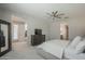 Spacious main bedroom with plush carpeting, a ceiling fan, TV on dresser, and ensuite bath and exterior access at 38082 W Santa Barbara Ave, Maricopa, AZ 85138