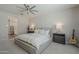 Neutral main bedroom with a ceiling fan, gray nightstands and lamps, and a comfortable bed with white comforter at 38082 W Santa Barbara Ave, Maricopa, AZ 85138