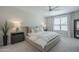 Neutral main bedroom featuring a ceiling fan, gray nightstands and lamps, large windows, and comfortable bedding at 38082 W Santa Barbara Ave, Maricopa, AZ 85138