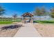 Picturesque pavilion with stone pillars overlooking a pond and manicured lawns offering a tranquil recreation spot at 38082 W Santa Barbara Ave, Maricopa, AZ 85138