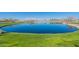 Serene community pond surrounded by lush green grass and landscaping, creating a peaceful outdoor space at 38082 W Santa Barbara Ave, Maricopa, AZ 85138