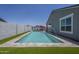 Relaxing pool with water feature and lounge area, framed by artificial turf, offering a private backyard oasis at 38082 W Santa Barbara Ave, Maricopa, AZ 85138