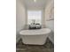 Bathroom featuring a soaking tub, white wainscoting, a modern fixtures, a window and wood-look floors at 3834 E Clarendon Ave, Phoenix, AZ 85018