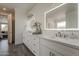 Bathroom featuring double sinks, white cabinets, lighted mirrors, modern fixtures and wood-look floors at 3834 E Clarendon Ave, Phoenix, AZ 85018