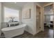 Bathroom featuring a soaking tub, white wainscoting, a window, and wood-look floors at 3834 E Clarendon Ave, Phoenix, AZ 85018