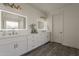 Bathroom featuring double sinks, white cabinets, lighted mirrors, modern fixtures and wood-look floors at 3834 E Clarendon Ave, Phoenix, AZ 85018
