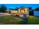 Exterior view of brick home featuring a large yard, driveway, and fire pit area, beautifully lit at twilight at 3834 E Clarendon Ave, Phoenix, AZ 85018