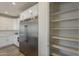 Kitchen showcasing stainless steel refrigerator, white cabinets, and a walk-in pantry at 3834 E Clarendon Ave, Phoenix, AZ 85018