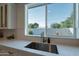 Bright kitchen features a stainless steel sink and faucet under a large window overlooking the backyard at 3834 E Clarendon Ave, Phoenix, AZ 85018