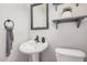 Well lit bathroom features a pedestal sink, neutral wall color, framed mirror and wood shelf at 4117 E Baylor Ln, Gilbert, AZ 85296