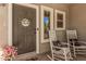 Inviting front porch with rocking chairs, a welcome sign on the door, and a pot of pink flowers at 4117 E Baylor Ln, Gilbert, AZ 85296