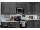 Modern kitchen featuring dark cabinets, stainless steel appliances, and white subway tile backsplash at 4352 N 91St Gln, Phoenix, AZ 85037