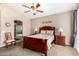 Bedroom with a wooden sleigh bed, soft carpet, ceiling fan, and an ensuite bathroom, offering comfort and convenience at 4738 N Greenview W Cir, Litchfield Park, AZ 85340