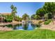 Scenic community pond with waterfall feature surrounded by lush landscaping and mature trees provides a serene environment at 4738 N Greenview W Cir, Litchfield Park, AZ 85340