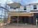 Unfinished two-story home with open garage door, scaffolding, and construction materials present at 5859 E Covey Ln, Phoenix, AZ 85054