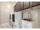 Well-equipped laundry room with modern washer, dryer, sink and ample storage cabinets at 6929 E Quill St, Mesa, AZ 85207