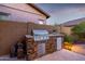 Outdoor kitchen with stone facade, built-in grill and beverage cooler adding a touch of luxury at 6929 E Quill St, Mesa, AZ 85207