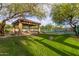 Lush green lawn leading to a shaded seating area overlooking the community tennis courts at 6929 E Quill St, Mesa, AZ 85207