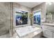 Elegant bathroom featuring a soaking tub, granite countertops, and large windows overlooking lush greenery at 6941 W Voltaire Ave, Peoria, AZ 85381