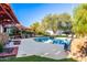 Sparkling pool with rock accents, a shaded lounge area, and a lush tropical backdrop, perfect for outdoor entertaining at 6941 W Voltaire Ave, Peoria, AZ 85381
