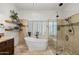 Bathroom with a soaking tub, a separate glass shower, and wood shelves with decorative vases at 7734 E Monica Dr, Scottsdale, AZ 85255