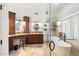 Bright bathroom featuring dual sinks, tub behind glass shower, vanity and wood cabinets at 7734 E Monica Dr, Scottsdale, AZ 85255