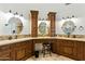 Bathroom featuring a vanity area with three mirrors and dark wood cabinetry with travertine flooring at 7734 E Monica Dr, Scottsdale, AZ 85255
