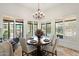Charming dining area with a round wood table, chandelier, and large windows overlooking the backyard at 7734 E Monica Dr, Scottsdale, AZ 85255