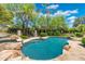 Inviting backyard pool with rock features, mature trees, and lush landscaping for relaxing outdoor living at 7734 E Monica Dr, Scottsdale, AZ 85255