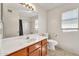 Bright bathroom featuring a vanity, large mirror, toilet, and window with blinds at 8871 W Maryland Ave, Glendale, AZ 85305