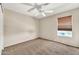 Simple bedroom with a window, ceiling fan, neutral walls, and carpeted floor at 8871 W Maryland Ave, Glendale, AZ 85305