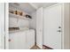 Functional laundry room with washer, dryer, storage shelves, and an exterior door at 8871 W Maryland Ave, Glendale, AZ 85305