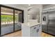 Kitchen island featuring quartz counters next to stainless refrigerator and sliding glass door at 9343 W Harmony Ln, Peoria, AZ 85382